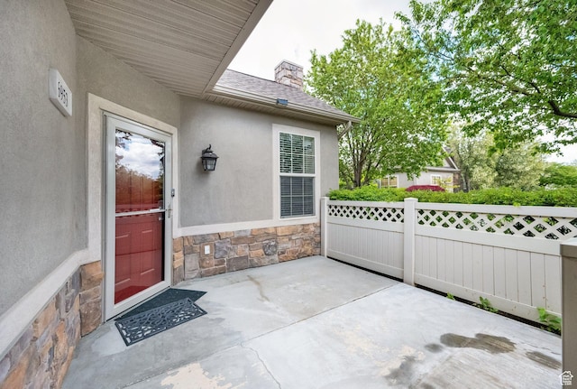 6953 S Country Home Ln W, West Jordan, UT 84084 - entrance to property featuring roof with shingles, a patio area, fence, stone siding, and stucco siding