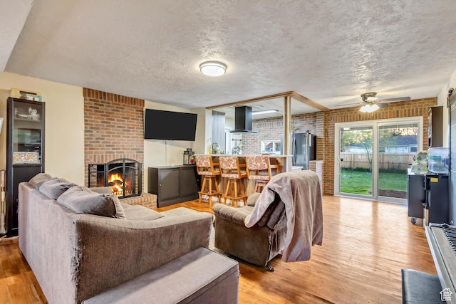 1072 S 1400 W, Salt Lake City, UT 84104 - living room with a ceiling fan, a textured ceiling, brick wall, a fireplace, and light wood-type flooring