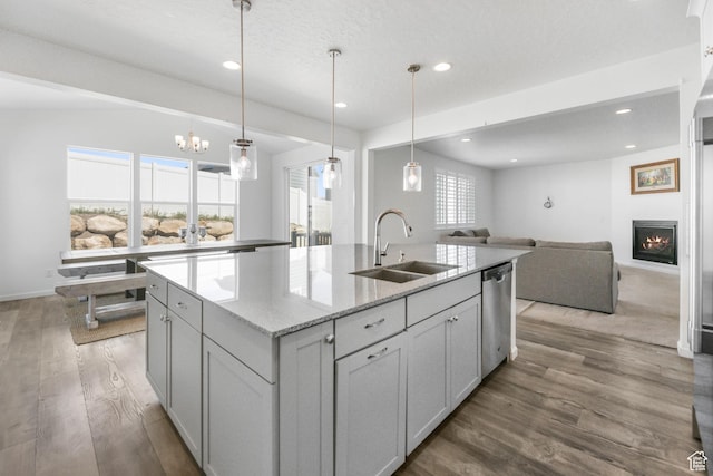 728 W Wild Hyacinth Dr, Saratoga Springs, UT 84045 - kitchen featuring a sink, an island with sink, open floor plan, wood finished floors, and stainless steel dishwasher