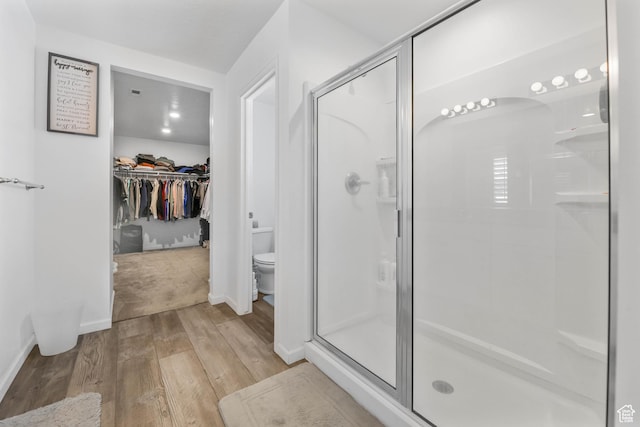 728 W Wild Hyacinth Dr, Saratoga Springs, UT 84045 - bathroom featuring a stall shower, a walk in closet, wood finished floors, and toilet