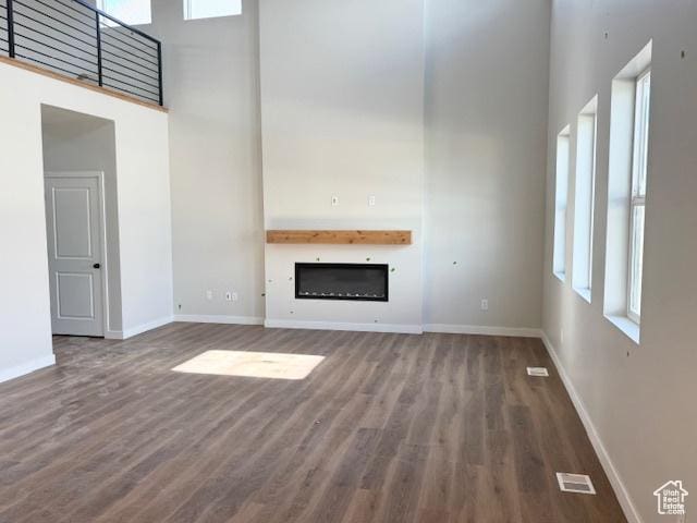 166 N Husker Ln Unit 1, Saratoga Springs, UT 84045 - unfurnished living room with a high ceiling, wood finished floors, a glass covered fireplace, and baseboards