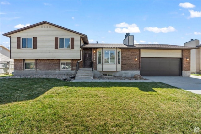 split level home with a chimney, brick siding, a front lawn, concrete driveway, and an attached garage