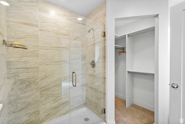 bathroom featuring baseboards, a walk in closet, and a stall shower
