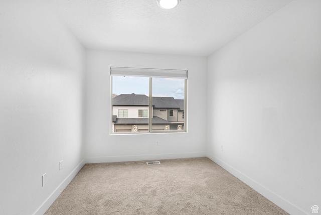 carpeted spare room featuring baseboards and visible vents