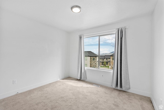 carpeted empty room with visible vents and baseboards