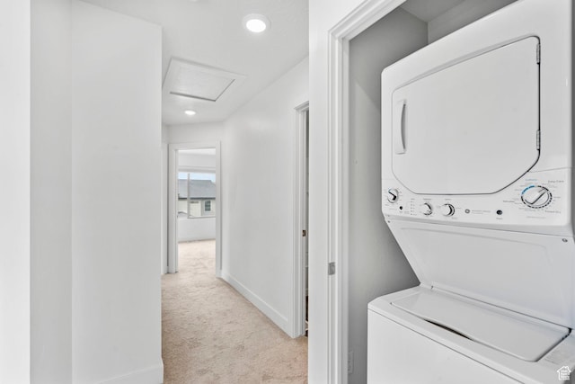 laundry area with laundry area, attic access, baseboards, stacked washer and clothes dryer, and carpet flooring