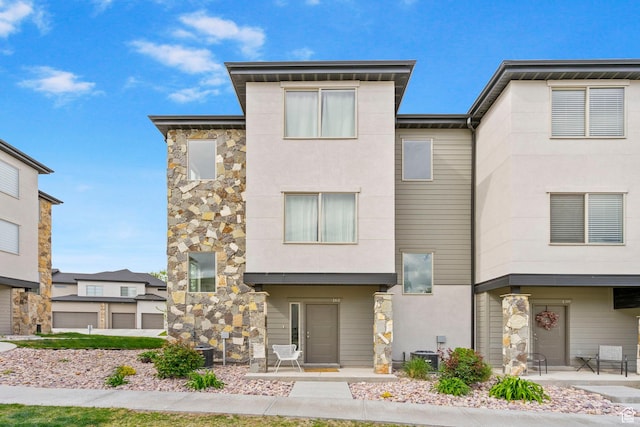 contemporary house featuring stucco siding, stone siding, and cooling unit