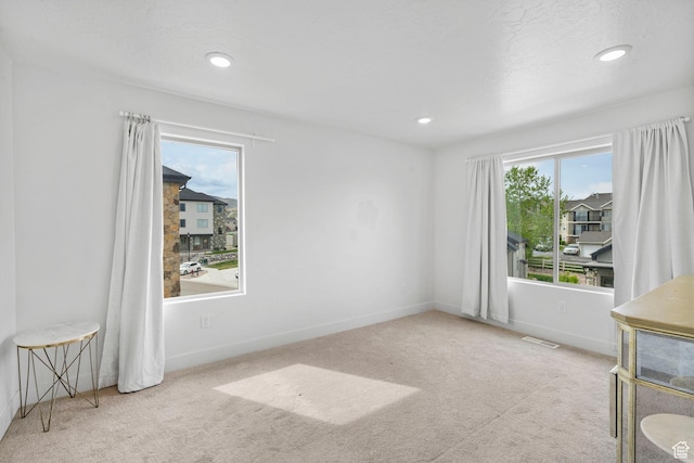 carpeted spare room featuring recessed lighting, baseboards, and visible vents