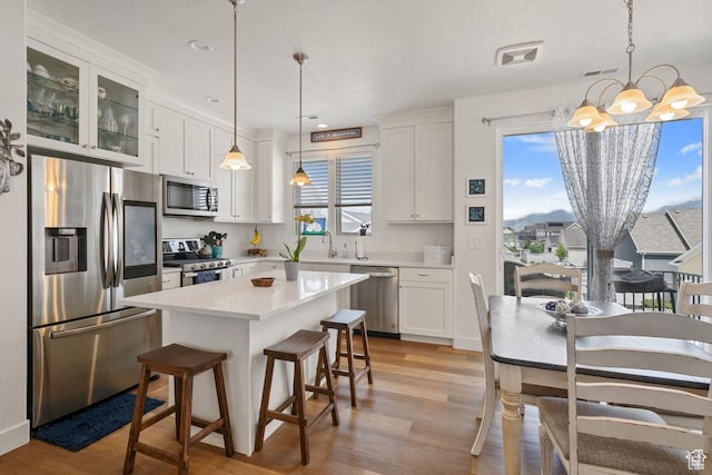 10983 S Lake Run Rd, South Jordan, UT 84009 - kitchen with stainless steel appliances, a sink, light wood finished floors, a chandelier, and white cabinets