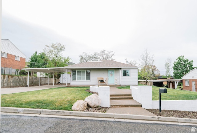 view of front facade with a front lawn, fence, an attached carport, and concrete driveway