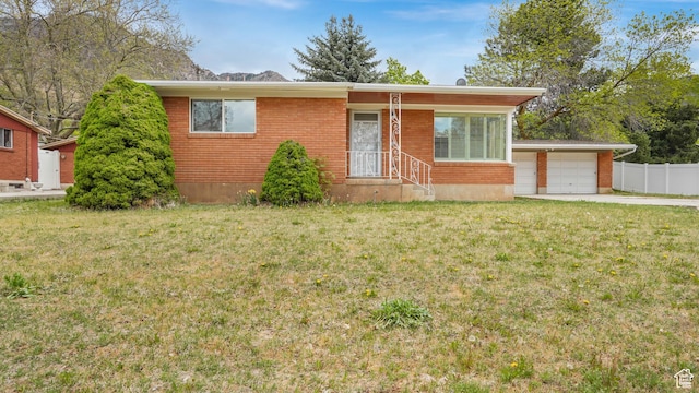 940 S Taylor E, Ogden, UT 84404 - view of front of house with fence, a front lawn, brick siding, a garage, and concrete driveway