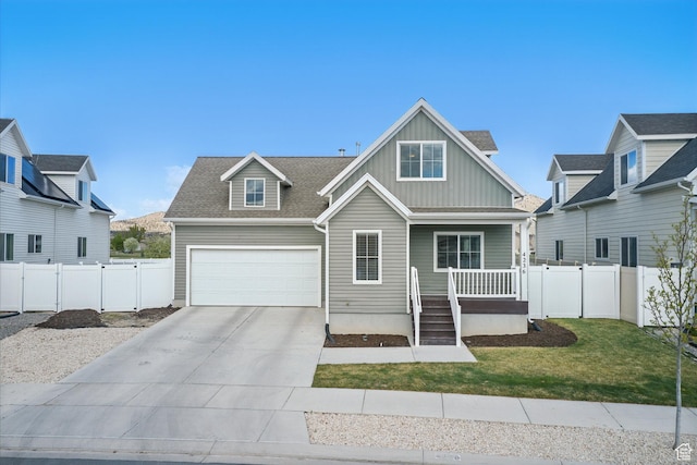 view of front facade featuring a front lawn, fence, covered porch, board and batten siding, and driveway
