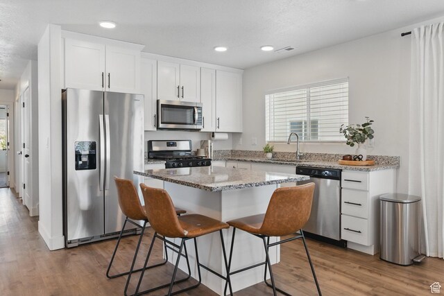 4236 N Magnolia Cir, Eagle Mountain, UT 84005 - kitchen with a sink, stainless steel appliances, wood finished floors, a kitchen island, and visible vents
