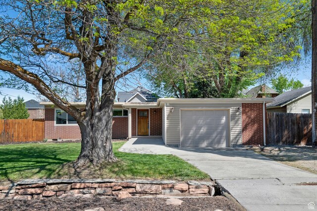 view of front of property with a garage, fence, a front yard, brick siding, and driveway