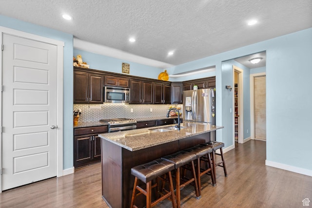 145 W 750 S, American Fork, UT 84003 - kitchen with dark brown cabinets, a sink, stainless steel appliances, wood finished floors, and a kitchen bar