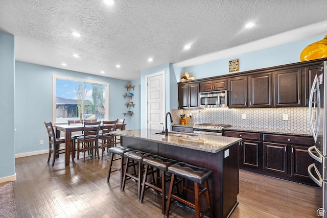 145 W 750 S, American Fork, UT 84003 - kitchen featuring a breakfast bar area, backsplash, wood finished floors, a sink, and stainless steel appliances