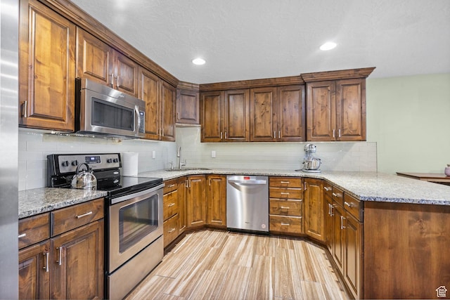 145 W 750 S, American Fork, UT 84003 - kitchen featuring light stone countertops, appliances with stainless steel finishes, a sink, a peninsula, and decorative backsplash