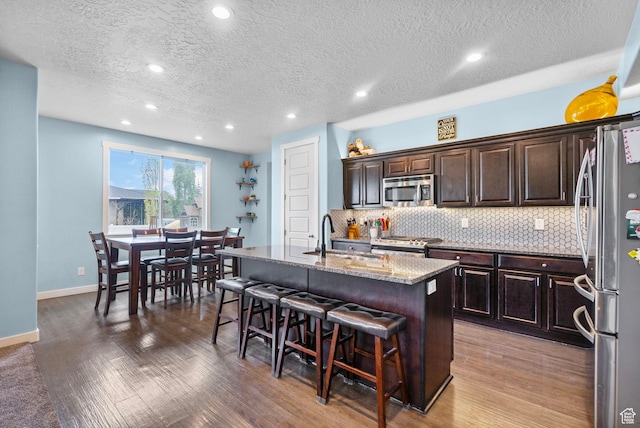 145 W 750 S, American Fork, UT 84003 - kitchen with a center island with sink, a kitchen bar, tasteful backsplash, a sink, and appliances with stainless steel finishes