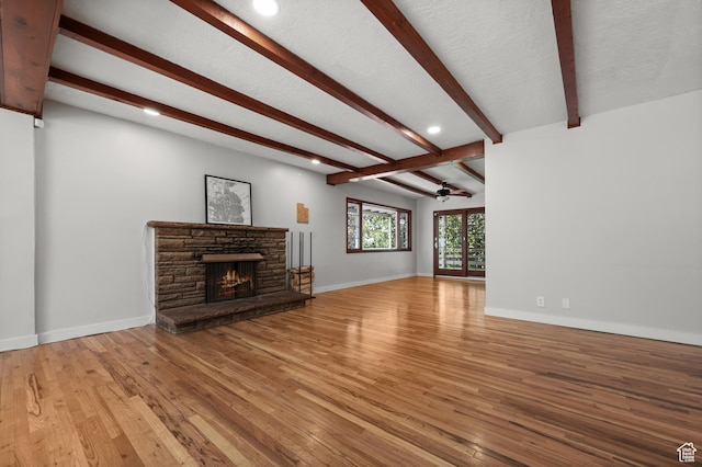 3581 E Yosemite Dr S, Millcreek, UT 84109 - unfurnished living room featuring a ceiling fan, light wood-type flooring, beamed ceiling, a stone fireplace, and recessed lighting
