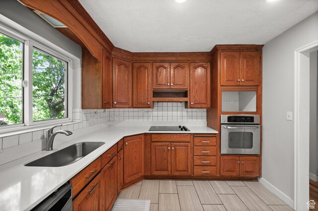 3581 E Yosemite Dr S, Millcreek, UT 84109 - kitchen featuring stainless steel appliances, a sink, backsplash, and light countertops