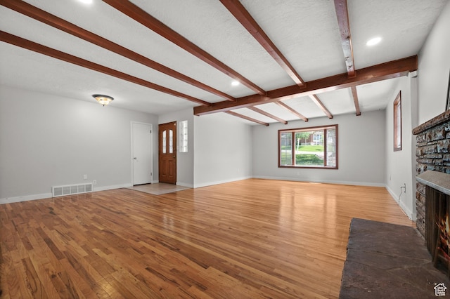 3581 E Yosemite Dr S, Millcreek, UT 84109 - unfurnished living room with a stone fireplace, wood finished floors, beamed ceiling, baseboards, and recessed lighting