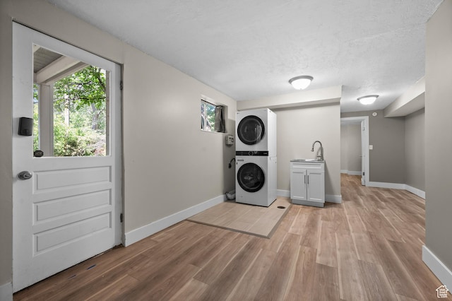 3581 E Yosemite Dr S, Millcreek, UT 84109 - clothes washing area featuring cabinet space, stacked washer and clothes dryer, light wood finished floors, baseboards, and a textured ceiling