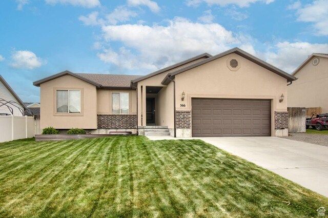 ranch-style house with a garage, a front lawn, fence, stucco siding, and driveway