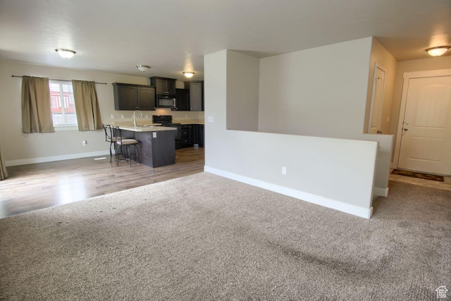 566 N 640 W, Tooele, UT 84074 - kitchen with black microwave, baseboards, light carpet, and a breakfast bar area