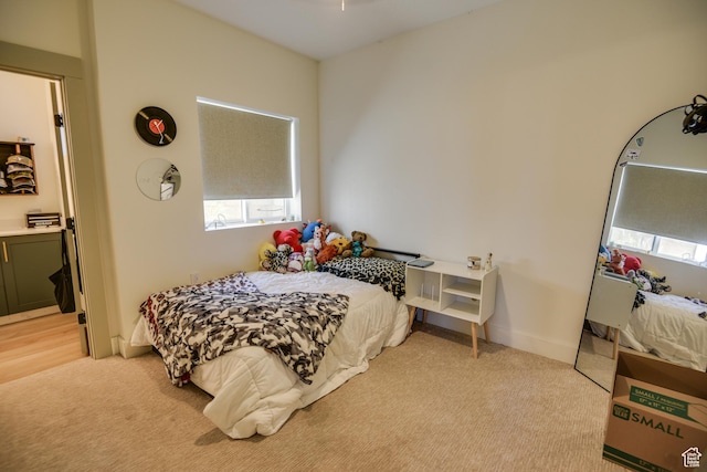 bedroom featuring light colored carpet and multiple windows
