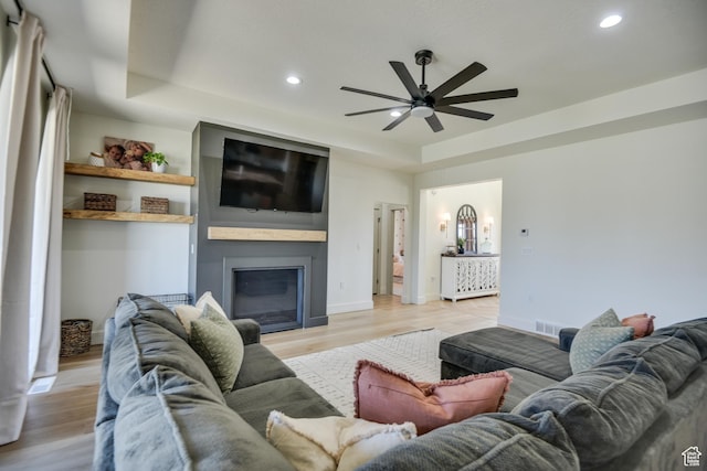 living area with a ceiling fan, visible vents, a raised ceiling, light wood finished floors, and recessed lighting