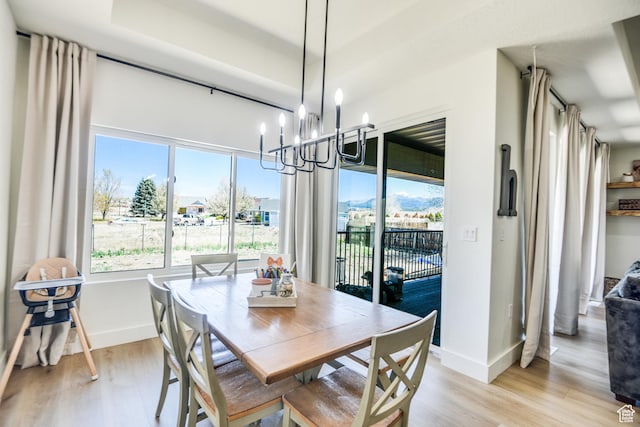 dining space with baseboards, light wood finished floors, and a chandelier