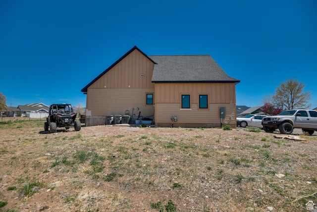 view of side of property with roof with shingles and fence