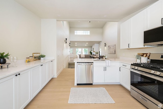 916 W 1150 S, Provo, UT 84601 - kitchen with white cabinets, stainless steel appliances, light wood-type flooring, and a peninsula