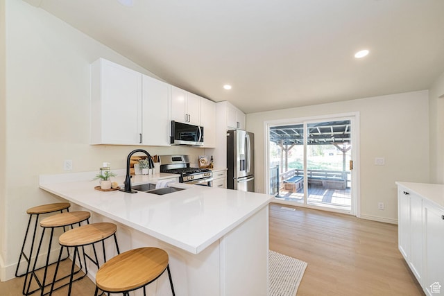 916 W 1150 S, Provo, UT 84601 - kitchen featuring a breakfast bar, light wood-style floors, light countertops, a sink, and appliances with stainless steel finishes
