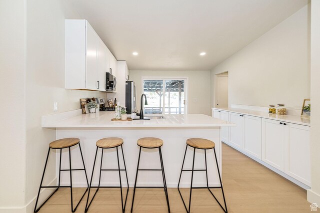 916 W 1150 S, Provo, UT 84601 - kitchen featuring a breakfast bar area, a sink, white cabinets, a peninsula, and stainless steel appliances