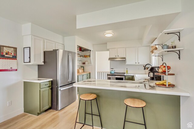 584 E Aspen Way, Centerville, UT 84014 - kitchen with open shelves, a peninsula, light wood-style floors, under cabinet range hood, and appliances with stainless steel finishes