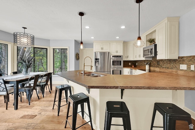 5078 S Iroquois Way E, Ogden, UT 84403 - kitchen with decorative backsplash, a sink, stainless steel appliances, recessed lighting, and light wood-style flooring