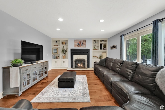 5078 S Iroquois Way E, Ogden, UT 84403 - living area featuring recessed lighting, a warm lit fireplace, built in shelves, and wood finished floors