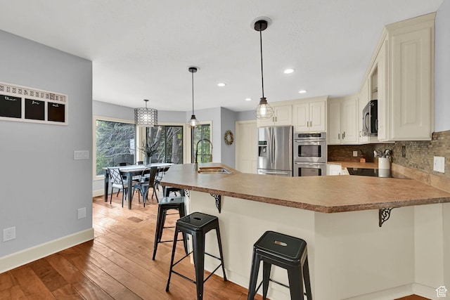 5078 S Iroquois Way E, Ogden, UT 84403 - kitchen with a sink, light wood-style floors, stainless steel appliances, a peninsula, and backsplash