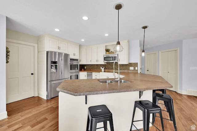 5078 S Iroquois Way E, Ogden, UT 84403 - kitchen with stainless steel appliances, a sink, light wood finished floors, and a kitchen bar