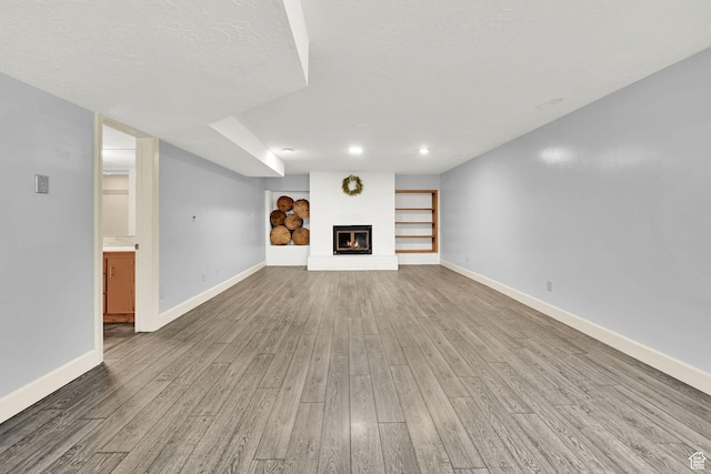 5078 S Iroquois Way E, Ogden, UT 84403 - unfurnished living room with recessed lighting, baseboards, a glass covered fireplace, and wood finished floors