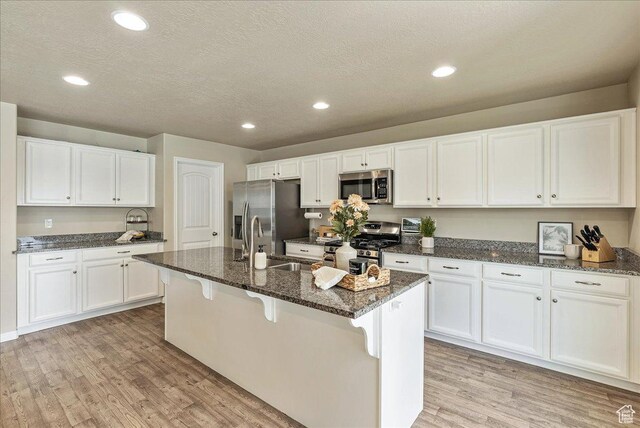 204 E 460 N, Vineyard, UT 84059 - kitchen featuring light wood-style floors, white cabinets, a sink, dark stone countertops, and appliances with stainless steel finishes