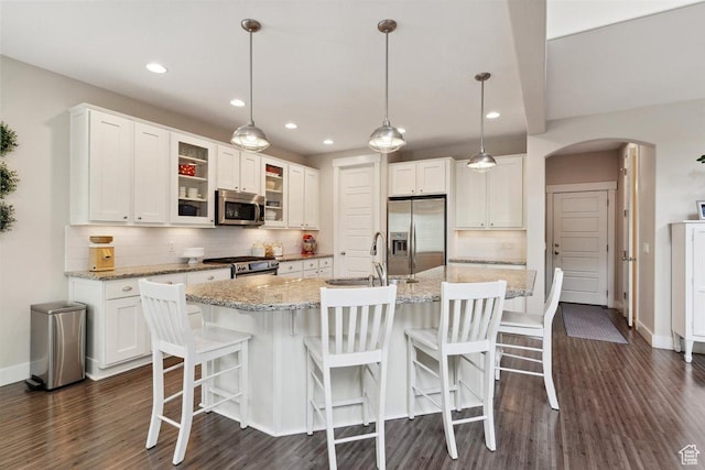 1485 E Peachtree Ln, Fruit Heights, UT 84037 - kitchen featuring a sink, arched walkways, stainless steel appliances, white cabinetry, and tasteful backsplash