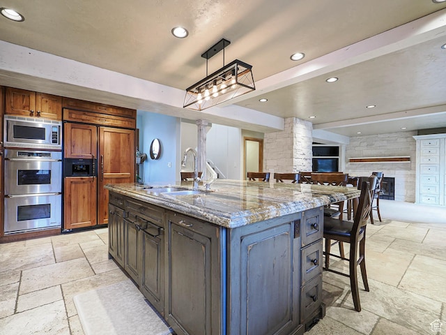 418 E Bridlewalk Ln, Murray, UT 84107 - kitchen featuring decorative columns, a kitchen bar, a sink, stone tile flooring, and built in appliances