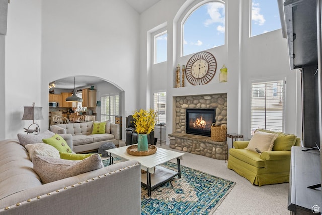6272 S Lake Fork Cir, Taylorsville, UT 84129 - living area with arched walkways, a stone fireplace, carpet, and a towering ceiling