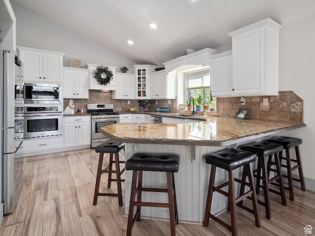 3540 N Elkview Dr, Eden, UT 84310 - kitchen featuring appliances with stainless steel finishes, a sink, a peninsula, white cabinetry, and lofted ceiling