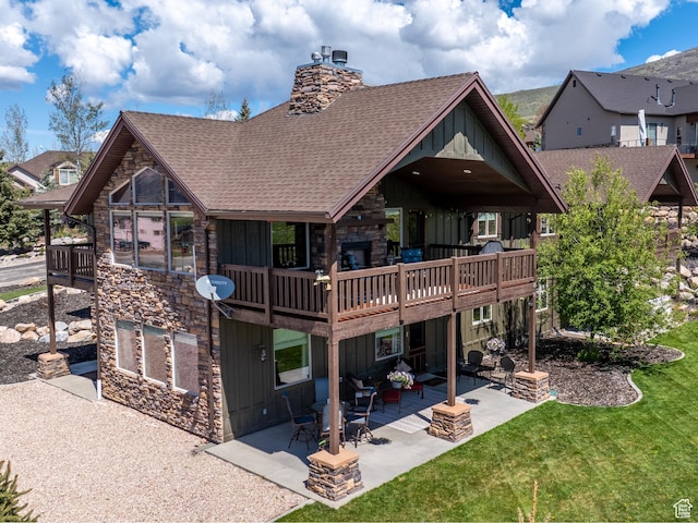3540 N Elkview Dr, Eden, UT 84310 - back of house with board and batten siding, roof with shingles, a lawn, a patio area, and stone siding