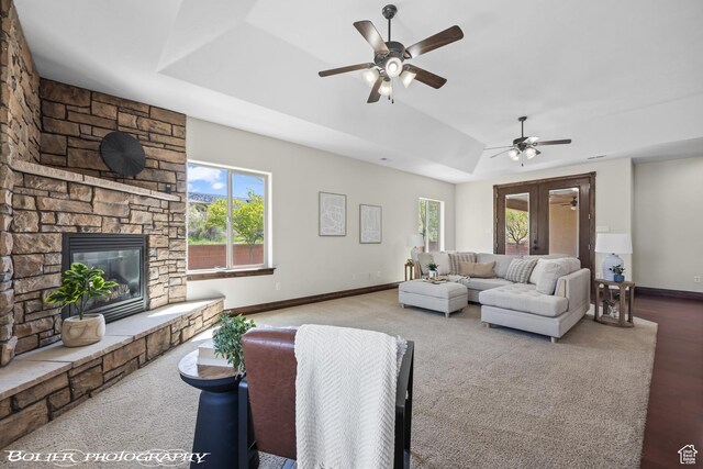 1328 N Parkside Dr, Cedar City, UT 84721 - living area with ceiling fan, carpet floors, a stone fireplace, baseboards, and a tray ceiling
