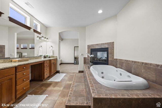 1328 N Parkside Dr, Cedar City, UT 84721 - full bath with visible vents, a tile fireplace, vanity, baseboards, and a whirlpool tub
