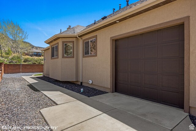 1328 N Parkside Dr, Cedar City, UT 84721 - view of side of property featuring a garage, fence, a mountain view, a shingled roof, and stucco siding